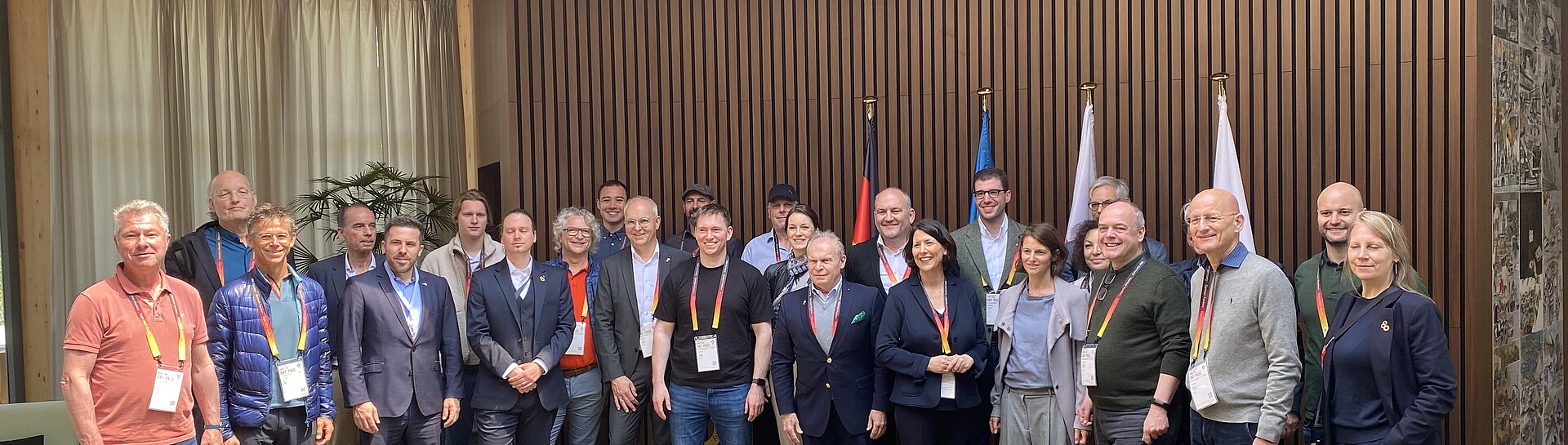 Gruppenfoto der Wirtschaftsdelegation Rheinland-Pfalz im Deutschen Pavillon der Expo 2025 in Osaka; Teilnehmerinnen und Teilnehmer stehen vor Flaggen und Holzverkleidung im Innenraum des Pavillons.
