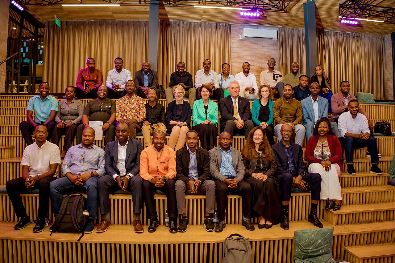 „Gruppenfoto von Teilnehmenden einer internationalen Business-Delegation bei einer Konferenz in Ruanda im modernen Veranstaltungssaal.
