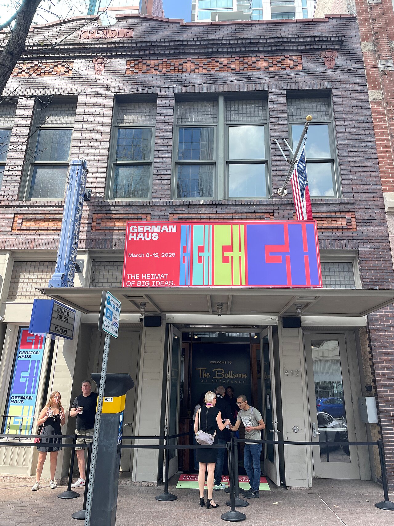 German-Haus-SXSW-2025-Austin.jpg Außenansicht des German Haus bei der SXSW 2025 in Austin, Texas, mit Besucher:innen vor dem Eingang und farbigem Branding der deutschen Delegation.