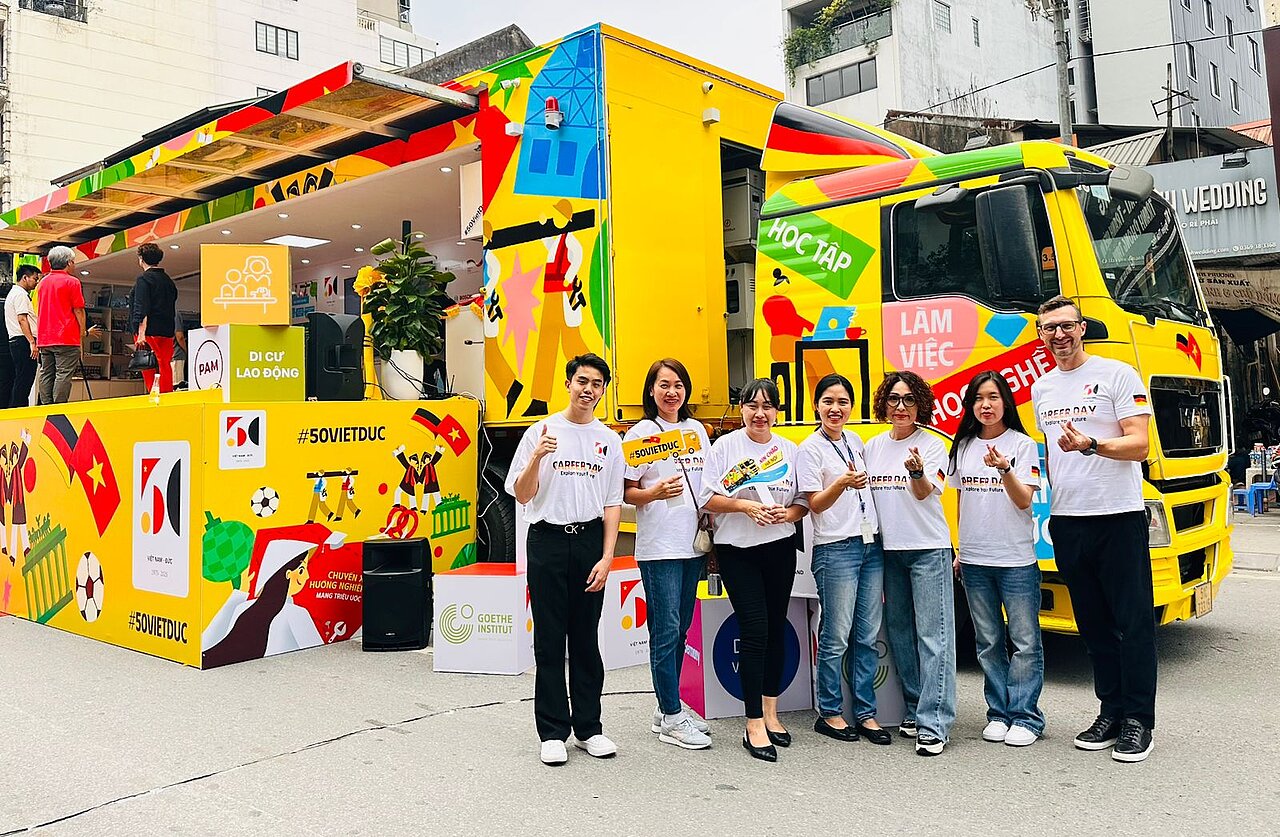 deutsch-vietnamesischer-karrieretag-50-jahre-partnerschaft.jpg Teilnehmerinnen und Teilnehmer beim deutsch-vietnamesischen Karrieretag vor einem bunt gestalteten Informations-Truck zum Jubiläum 50 Jahre Partnerschaft Vietnam–Deutschland.